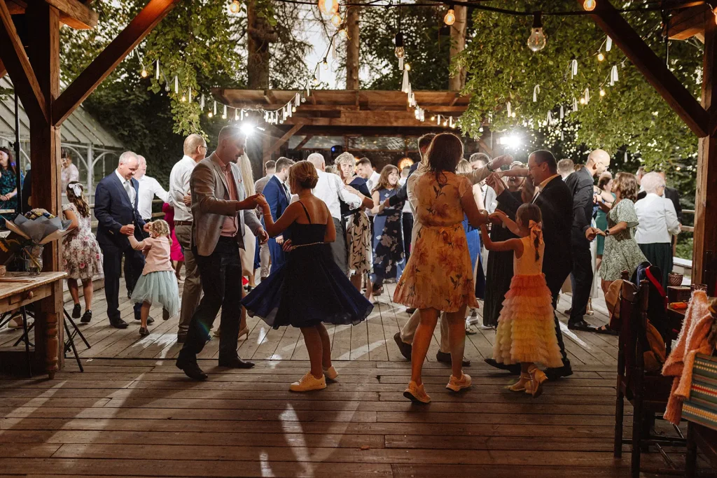 Pełny parkiet tańczących osób na weselu w plenerze